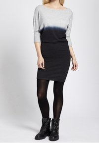 Grauer und schwarzer Gradient-Pulloverkleid mit Dreiviertelärmeln, weichem Stricktextil und enganliegendem Schnitt, kombiniert mit schwarzen Combat Boots.