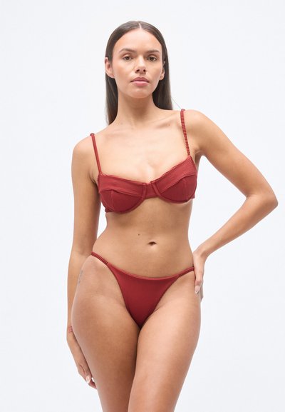 Σετ κόκκινου μπικίνι με ραβδώσεις, που περιλαμβάνει ένα δομημένο τοπ με ενισχυμένο στήριγμα και ρυθμιζόμενες τιράντες, καθώς και ένα ταίριαστο κάτω μέρος με ψηλή γραμμή. Λείο υλικό, με ελάχιστες διακοσμητικές λεπτομέρειες.