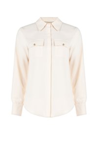 Blusa color crema realizzata in tessuto morbido, con colletto classico, maniche lunghe, due tasche sul petto con dettagli in bottone e orlo arrotondato.