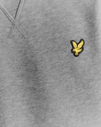 Sweatshirt gris avec une texture douce, arborant un petit logo d'oiseau brodé jaune sur le côté gauche. Design simple et décontracté.