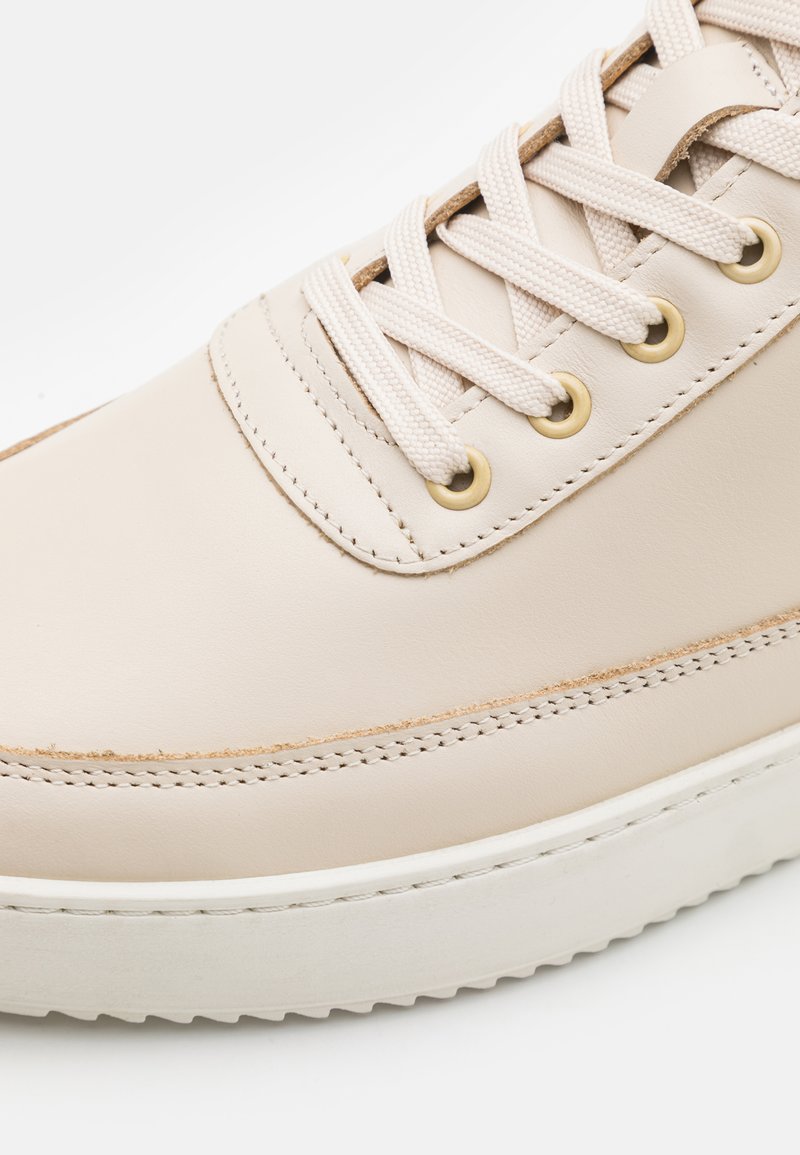 Helle beige Leder-Sneaker mit weißer Gummisohle, runder Zehenform, flachen Schnürsenkeln und goldenen Ösen; verfügt über genähte Akzente entlang der Kanten.