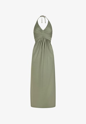 Zwei Frauen posieren in einer sonnenbeschienenen Umgebung. Eine trägt ein grünes Maxikleid mit tailliertem Oberteil; die andere trägt ein gemustertes Wickelkleid in Blau und Schwarz.