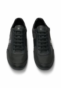 Czarne sneakersy z siateczkowymi i syntetycznymi panelami, płaskimi sznurówkami, gumowymi podeszwami oraz detalem logo z boku. Gładka faktura o smukłym designie.