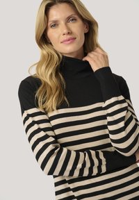 Maglione a collo alto a righe nere e beige con maniche lunghe. Presenta un collo a coste spesso e un tessuto morbido e textured.