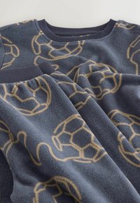 Navy sininen fleecesweatshirt, jossa on pehmeä pinta. Värissä on beige jalkapallokuvio. Vahvistettu pyöreä kaula-aukko ja hihansuut.