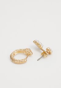 Goldfarbene Ohrringe mit einem schlangenförmigen Ring und einem Stecker mit kleinen runden Perlen. Strukturelle Details am Ring verbessern das Design.