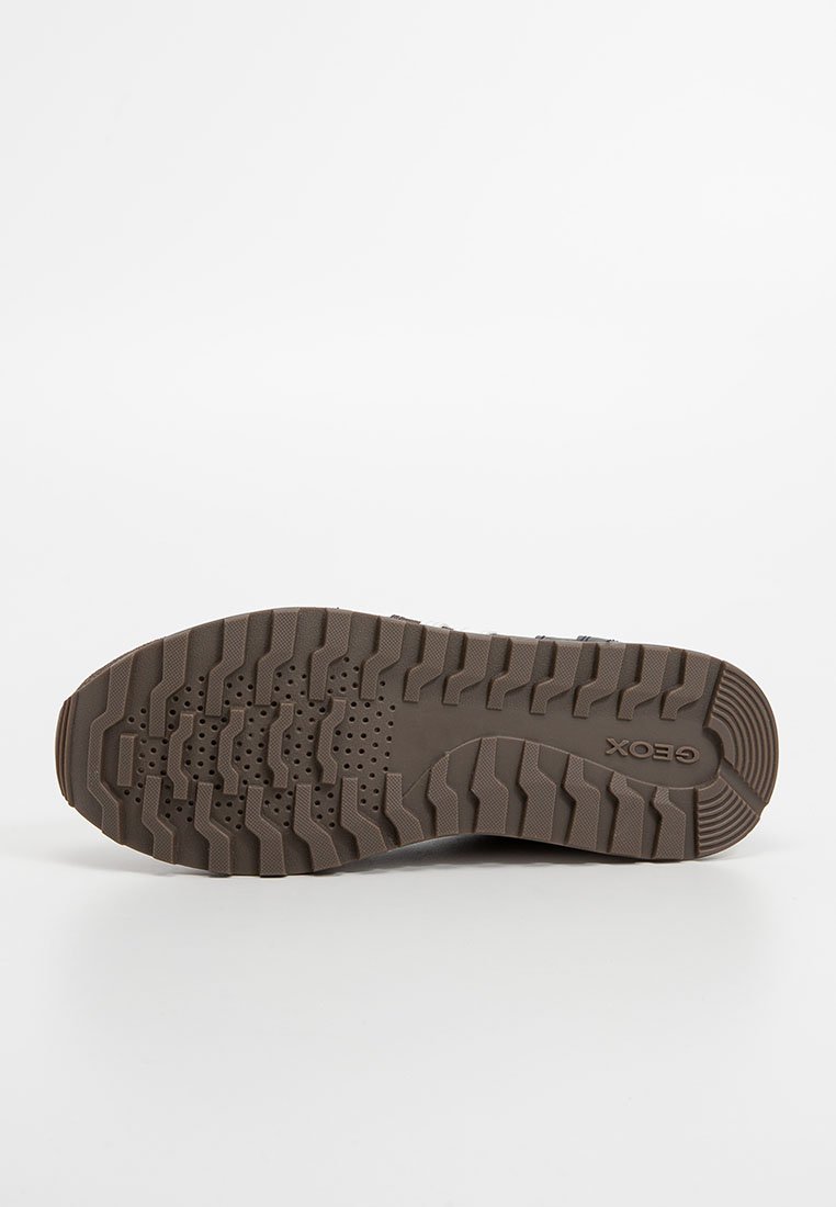 Semelle de chaussure en caoutchouc marron avec de profonds crampons et des trous de drainage pour une meilleure traction. Elle arbore un logo en relief "Geox" au niveau du talon. Design texturé sur toute la surface.