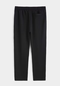 Pantalon de sport noir en tissu doux et extensible, doté d'une ceinture élastique et d'une petite poche à l'arrière, du côté droit.