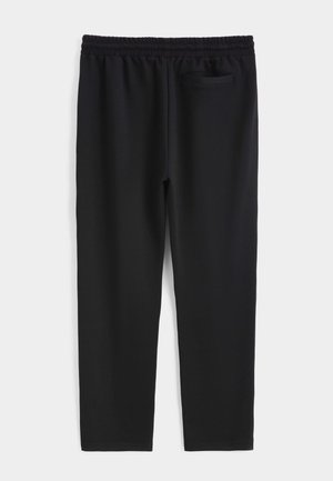 Pantalon de sport noir en tissu doux et extensible, doté d'une ceinture élastique et d'une petite poche à l'arrière, du côté droit.