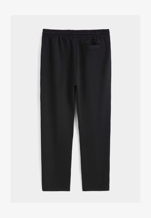 Pantalon de sport noir en tissu doux et extensible, doté d'une ceinture élastique et d'une petite poche à l'arrière, du côté droit.