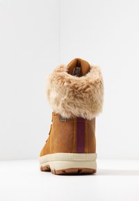 Bruine leren laars met nepbonten kraag, getextureerd oppervlak, paarse accentstreep en beige rubberen zool. Voorzien van een waterdicht ontwerp.