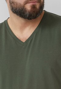 Donkergroene V-hals t-shirt gemaakt van zacht materiaal, met een subtiel s.Oliver logo geborduurd op het linkerbovenbeen.