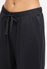 Svarta loungebyxor i mjukt tyg, med resår i midjan och en rosettdetalj samt avslappnad passform för komfort.