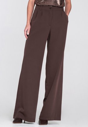 Brązowe spodnie o szerokich nogawkach z gładkiej tkaniny, z przednimi kieszeniami i pojedynczą plisą z przodu. Zapięcie na guzik w pasie.