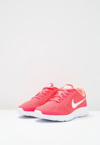 Pair of vibrant pink Nike running shoes with white swoosh logos and white soles on a plain white surface.