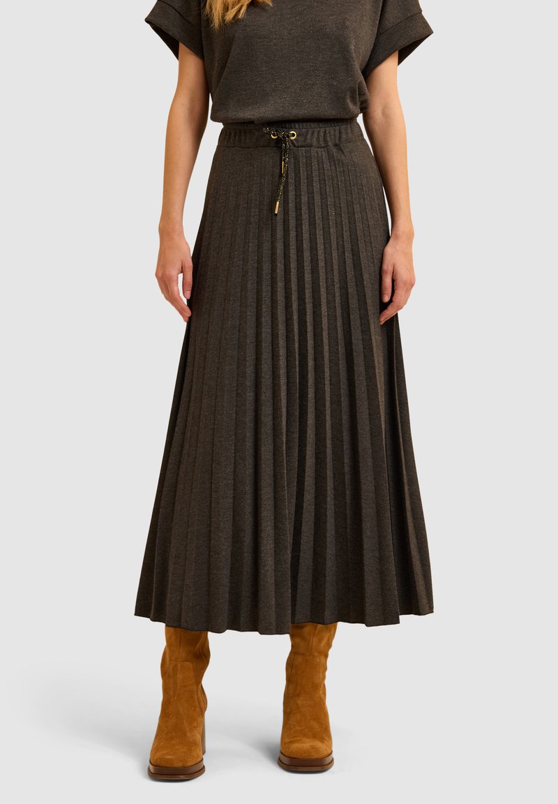 Donkergrijze geplooide midirok van zachte stof met een elastische tailleband en trekkoord, gecombineerd met tan kleurige suède enkellaarsjes.