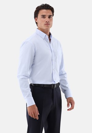 Hellblau gestreiftes Hemd mit Button-Down-Kragen, Brusttasche und langen Ärmeln, kombiniert mit dunkler Hose und schwarzem Gürtel.