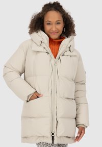 Veste bouffante légère beige clair avec un col haut, une fermeture éclair et des poches latérales. Elle présente une texture douce et une coupe décontractée.