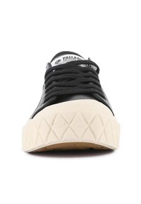 Sneaker nera con punta in gomma, suola testurizzata color crema e lacci piatti. Presenta un logo sulla linguetta e un design semplice e minimalista.