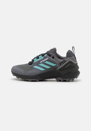Chaussure de trail Adidas Terrex grise et noire avec des bandes turquoise, étiquette Gore-Tex et semelle robuste pour une utilisation extérieure.