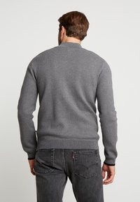 Grå tröja med rund halsringning, ribbade ärmslut och nederkant. Tillverkad av ett mjukt stickat material med en jämn textur och en enkel design.