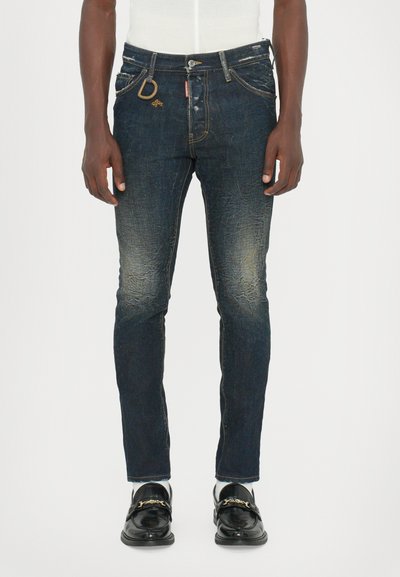 Dunkelblaue Denim-Jeans mit schlankem Schnitt, leichter Ausbleichung und subtiler, distressed Textur. Ausgestattet mit goldfarbenen Beschlägen und einem D-förmigen Akzent.