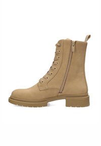 Stivale alla caviglia in pelle marrone con punta tonda, lacci frontali e cerniera laterale. Presenta una finitura testurizzata e una suola in gomma spessa.