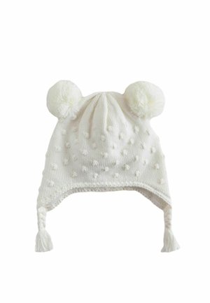 Weiße gestrickte Babymütze mit zwei Bommel oben, erhabenem Punktmuster und geflochtenen Quasten, die von jeder Ohrklappe hängen.