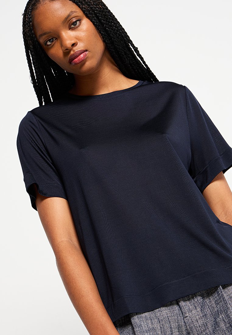 Marineblaues T-Shirt mit kurzen Ärmeln, rundem Halsausschnitt, glatter Textur, lässigem Schnitt und kontrastierenden Nahtdetails am Saum und an den Ärmeln.