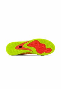 Semelle d'une sneakers avec des couleurs néon vives vert et rouge, des rainures texturées et un détail de logo en noir.