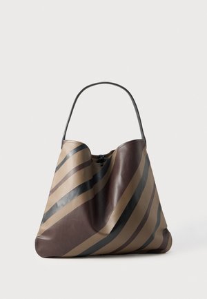 Un grand sac à bandoulière rayé marron et beige avec une longue anse noire, sur un fond clair uni.
