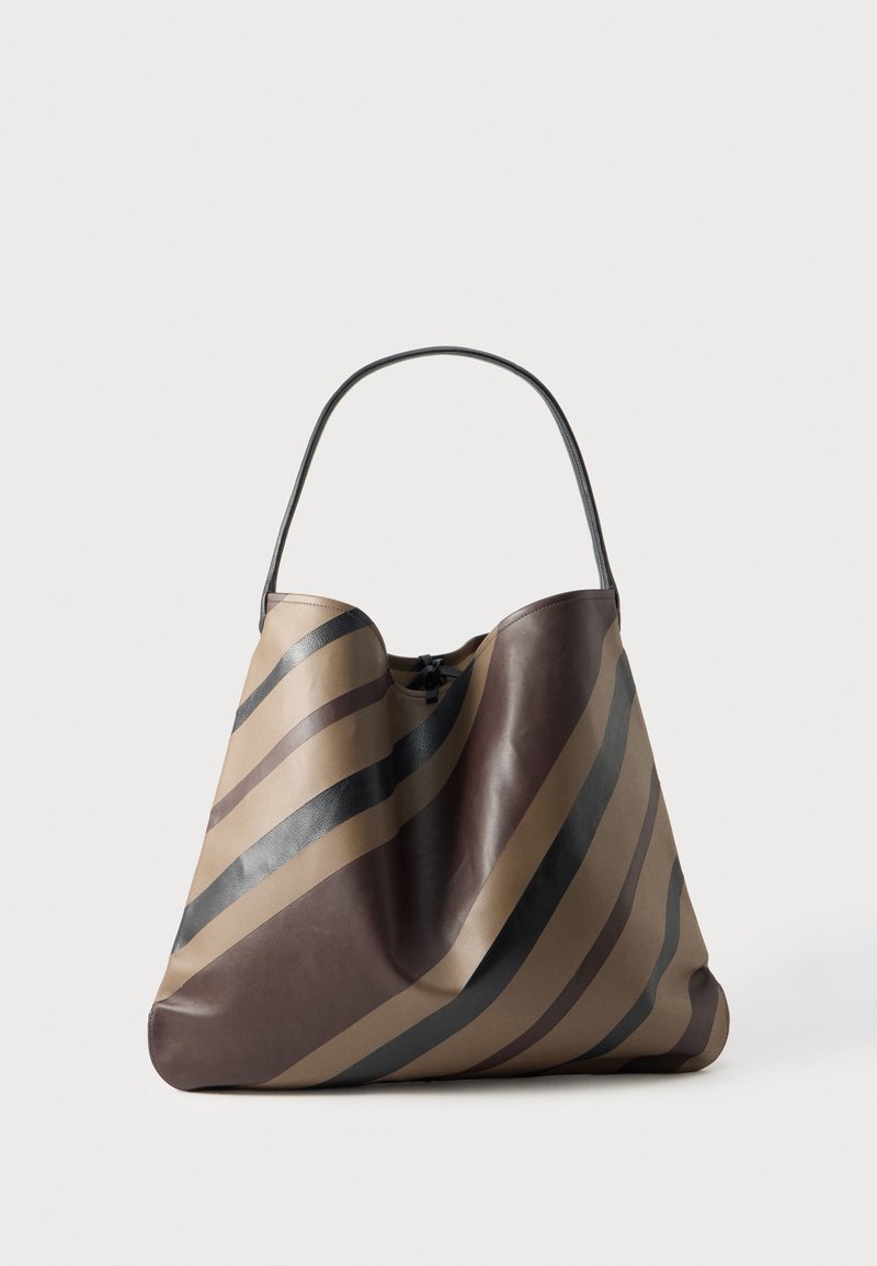 Un grand sac à bandoulière rayé marron et beige avec une longue anse noire, sur un fond clair uni.