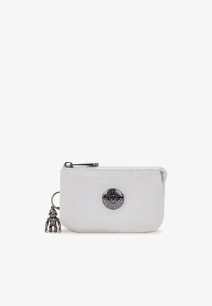 Biały skórzany portfel z zamknięciem na zamek, z okrągłym srebrnym logo i małym metalowym brelokiem w kształcie małpki.