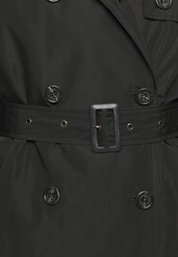 Černý trenčkot s dvouřadým zapínáním, velkými knoflíky, páskem v pase a hladkou, texturovanou látkou.