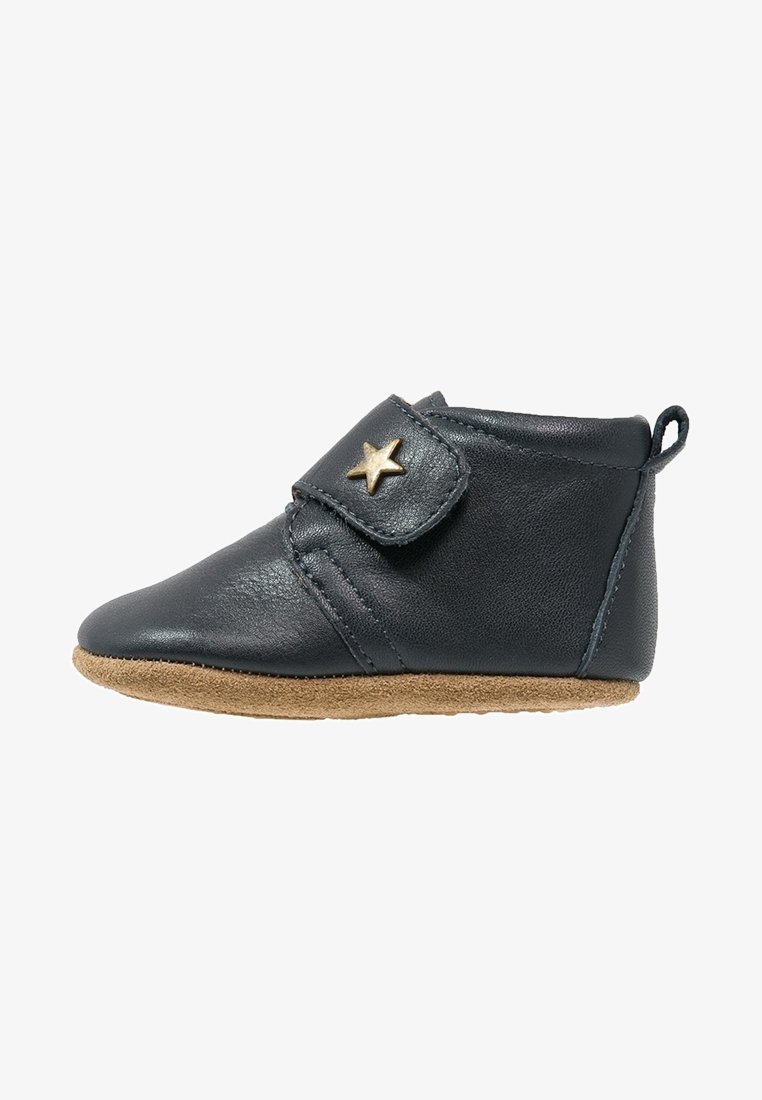 Dark blue leather bootie with a soft tan sole, featuring a strap with a gold star accent. Smooth texture and rounded toe design.