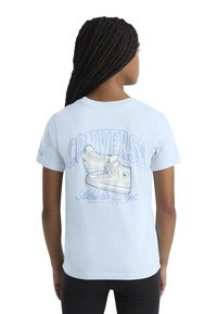 Šviesiai mėlynas medvilninis marškinėlis su Converse sportbačių grafika, po kuria bold rašmenimis užrašyta "Converse Athletic Dept."