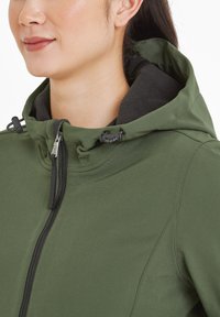 Green soft shell jacket with a zippered front, adjustable hood, and black fleece lining. Features smooth texture and minimalistic design accents.