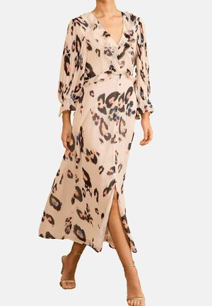 Femme portant une robe midi beige avec imprimé léopard multicolore, col en V, boutonnage sur le devant, fente et manches bouffantes trois-quarts avec poignets.