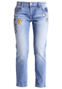 Ljust blå denimjeans med rak passform, prydda med olika färgglada broderade lappar, inklusive en cocktail och en musiknot.