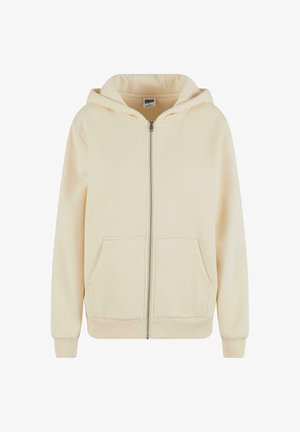 Bež dukserica sa patentnim zatvaračem, izrađena od mekog materijala, s kapuljačom, prednjim džepovima, rebrastim manžetama i rubom, s glatkom završnom obradom i minimalističkim dizajnom.