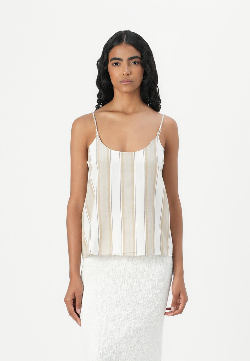Stripet beige og hvit tanktop med tynne stropper, som har en rund utringning og løs passform. Stoffet ser lett og mykt ut.