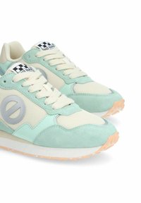 Sneakers verde menta e crema con pannelli in rete e accenti in suede, dotati di un dettaglio rotondo del logo e una suola in gomma testurizzata.