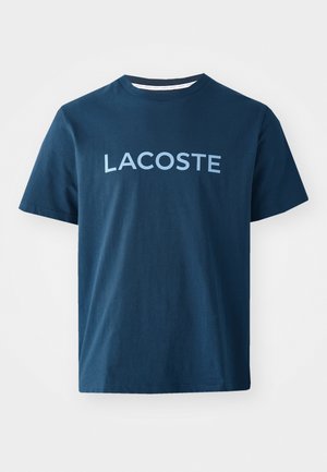 Navyblauwe katoenen T-shirt met korte mouwen en ronde hals. Kenmerkt zich door het woord "LACOSTE" in lichtblauw over de borst. Gladde textuur.
