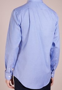 Camicia a maniche lunghe azzurro chiaro con motivo a scacchi, polsini abbottonati e orlo curvo. Realizzata in tessuto flessibile. Dettagli di cucitura visibili.