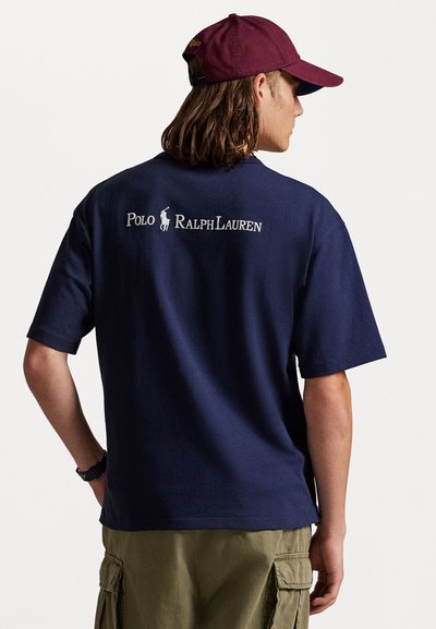 Σκούρο μπλε κοντομάνικο t-shirt με λαιμόκοψη, που διαθέτει κείμενο και λογότυπο "Polo Ralph Lauren" σε λευκό χρώμα στην πλάτη. Μαλακό βαμβακερό υλικό.