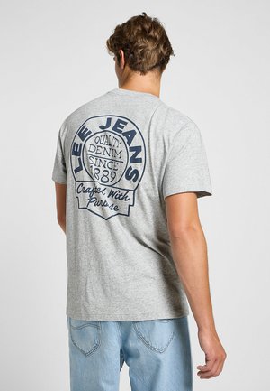 Harmaa lyhythihainen t-paita, jossa on laivastonsininen graafinen printti selässä. Tässä on tekstit "Lee Jeans", "Laadukas farkkukangas vuodesta 1889" ja "Tarkoituksella valmistettu".