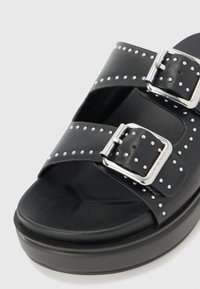Melnas platform sandales ar diviem ādas siksniņām, sudraba sprādžu uzgaļiem un studētiem akcentiem malās. Strukturēta pēda.