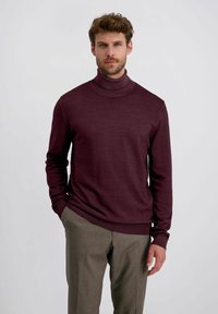 Bordeaux coltrui sweater van een zachte breikwaliteit, met lange mouwen en een getailleerd ontwerp, gecombineerd met lichtbruine broeken.