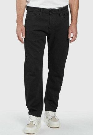 Schwarze Jeans aus Denim mit geradem Bein, fünf Taschen und Metallknopfverschluss. Getragen mit weißen Sneakers.