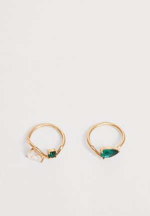 Deux bagues en or avec des pierres précieuses en forme de goutte, l'une avec des pierres claires et vertes, l'autre avec une pierre verte unique.